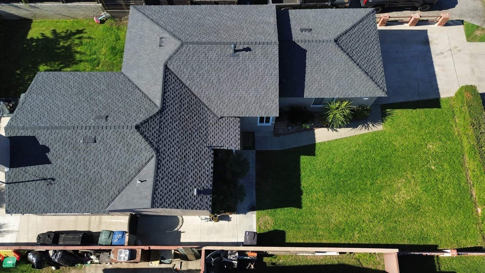 Aerial view of a house with multiple modern roofing styles and a green lawn.