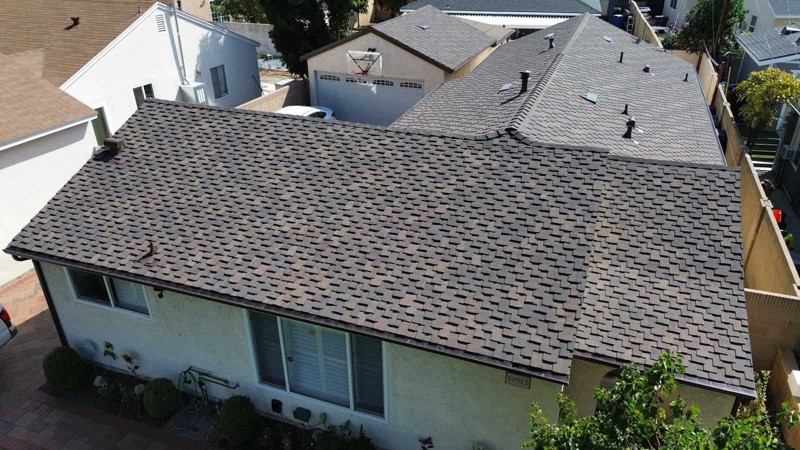 Aerial view of a house with new asphalt shingle roof installation.