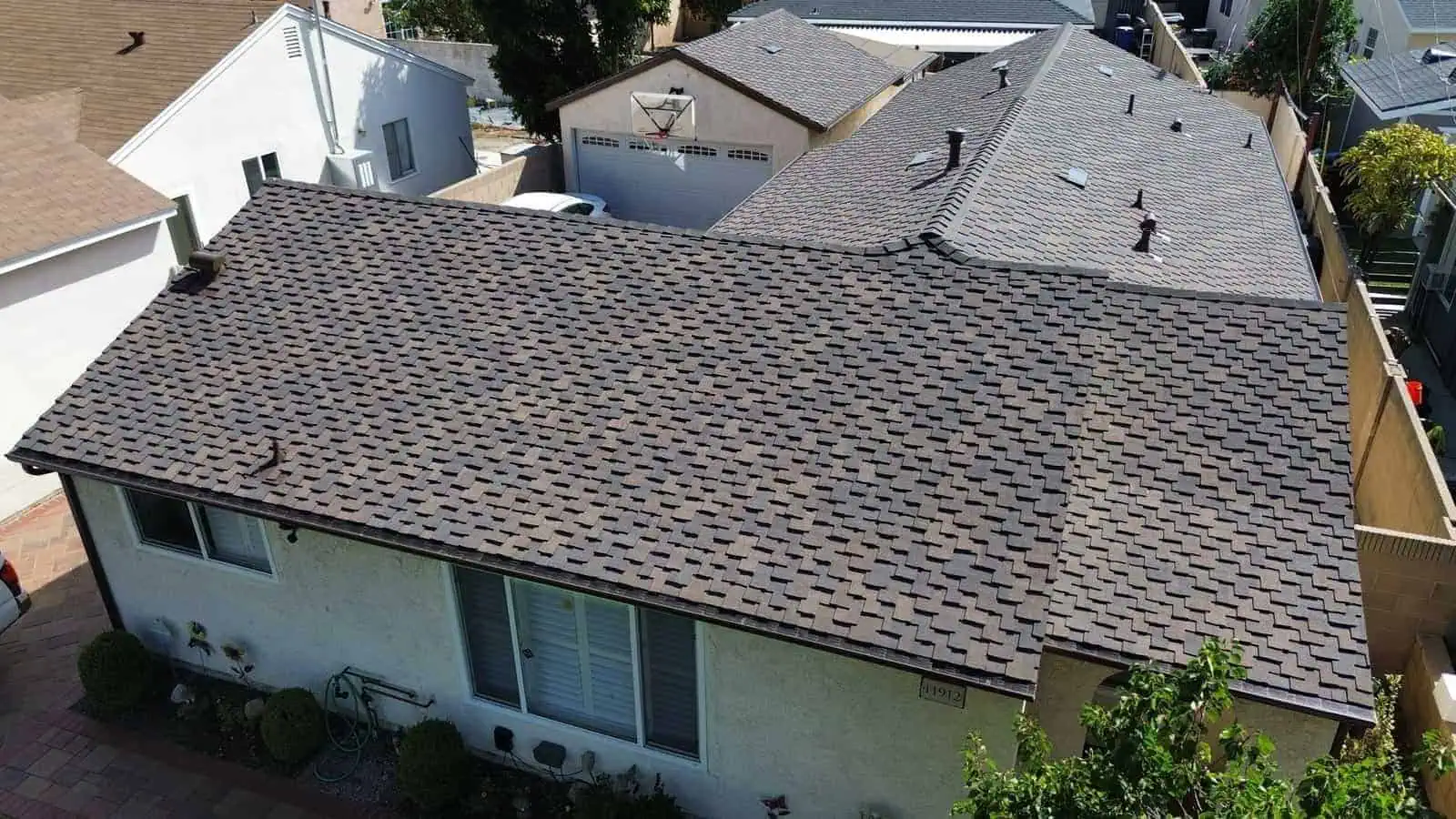 Aerial view of a house with new asphalt shingle roof installation.
