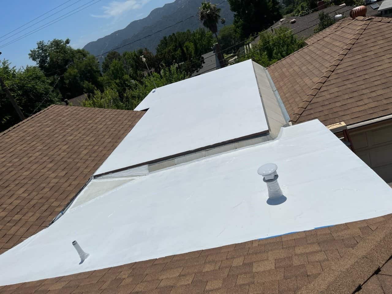 White roof coating with vents and skylight in residential neighborhood.