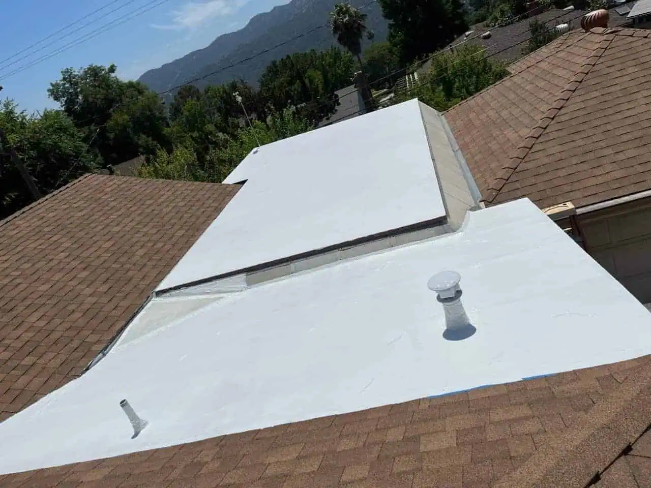 White roof coating with vents and skylight in residential neighborhood.