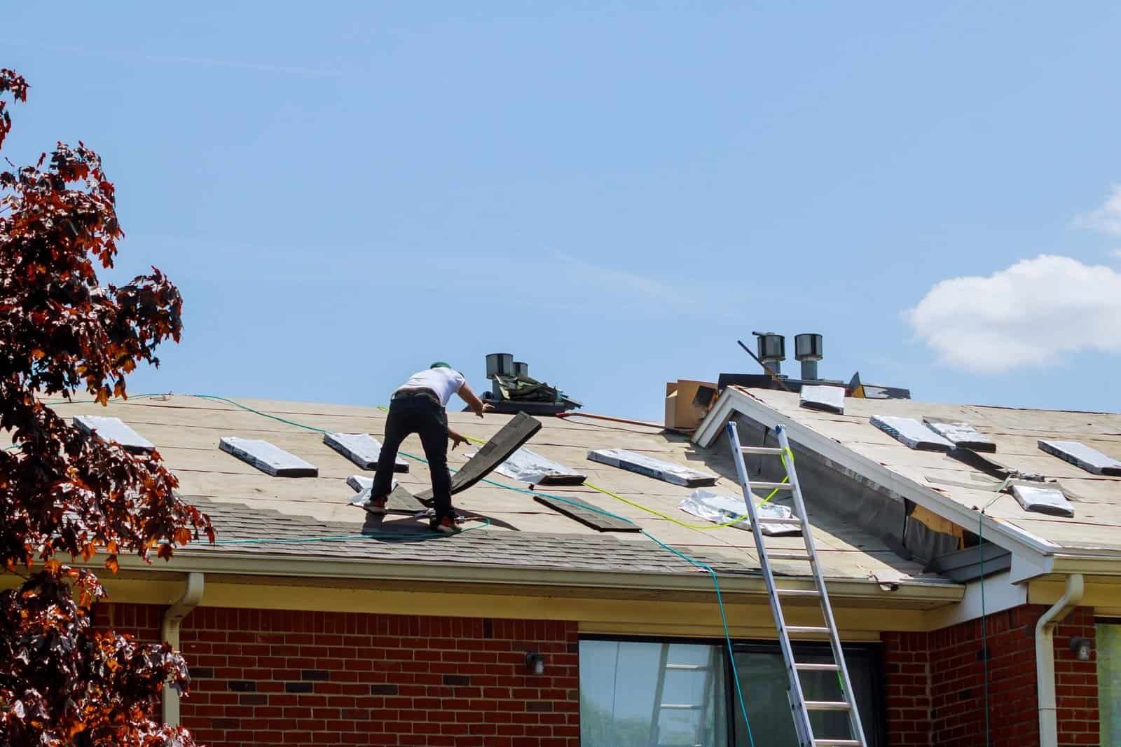 Roofing contractor working on a residential roof with shingles and tools.