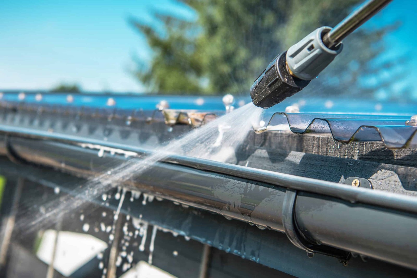 Professional roof cleaning with high-pressure water spray on residential roof.