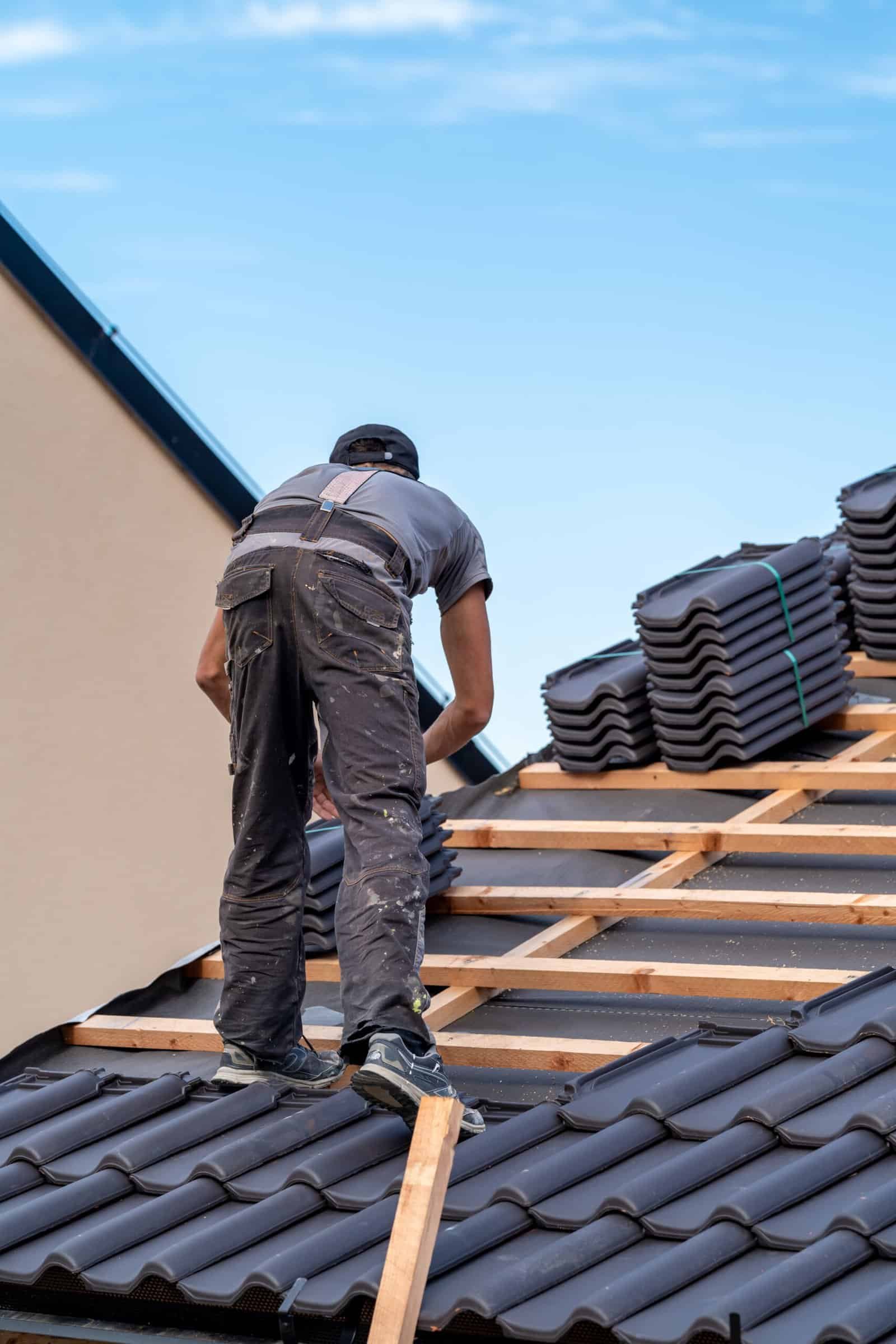 Roofing worker installing roof tiles on a residential building.